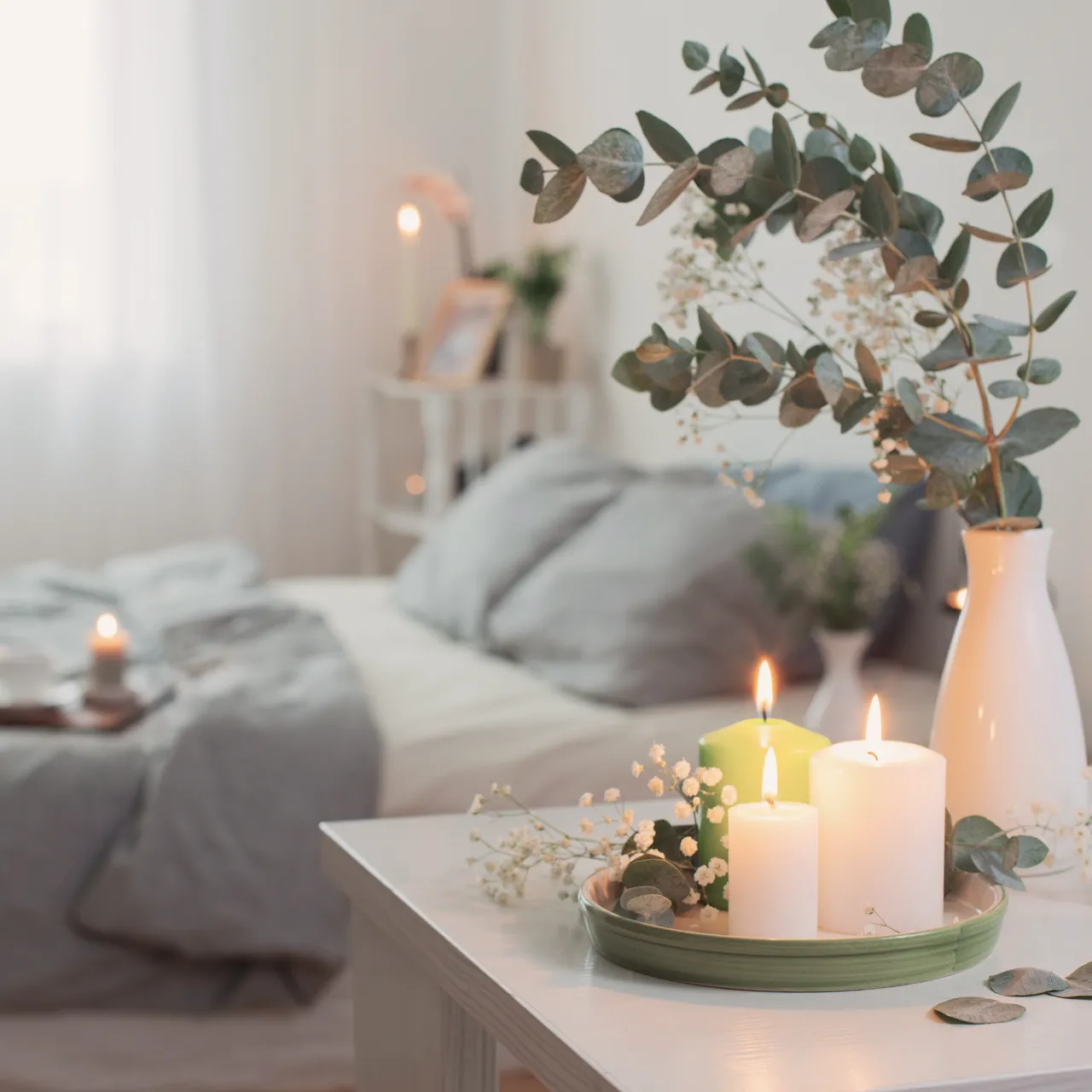 Bedroom with plants and scented candles on either side of the bed.